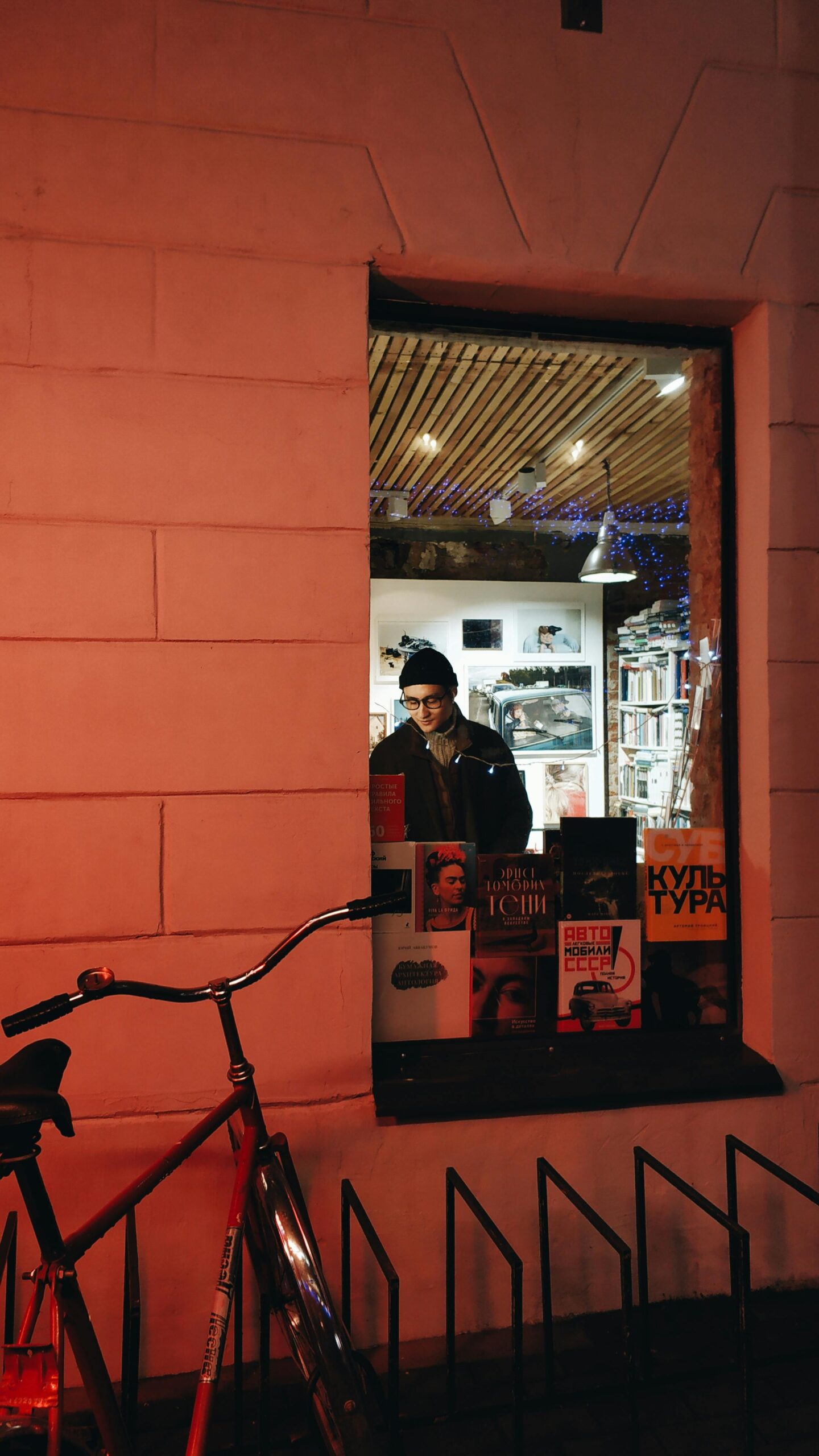 Мужчина стоит в книжном магазине и рассматривает книги