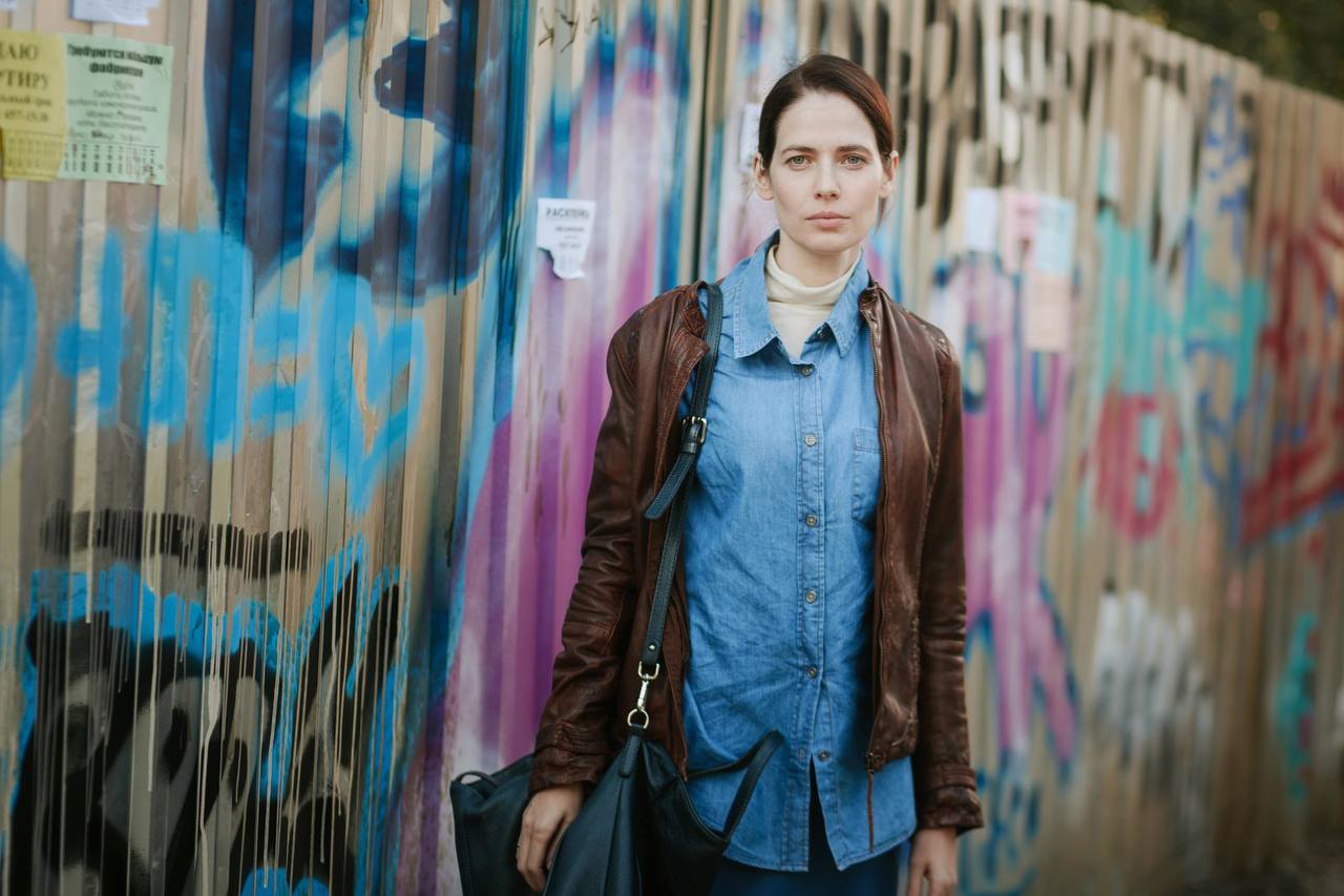 Сцена из сериала „Маяк“ Персонаж на фоне стены — напряжённая и атмосферная сцена сериала „Маяк“